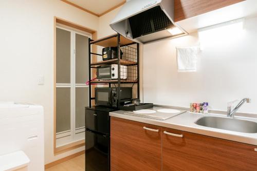 a small kitchen with a sink and a microwave at Ferio in Tokyo