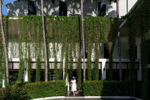 a woman standing in front of a building with plants at Proud Phuket, Naiyang Beach in Nai Yang Beach