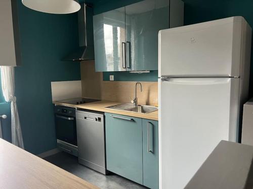 La cuisine est équipée de placards bleus et d'un réfrigérateur blanc. dans l'établissement Chez Rockette, à Verdun-sur-Meuse