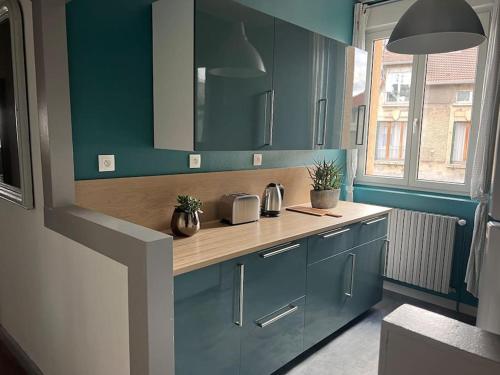 une cuisine avec des placards bleus et un comptoir en bois dans l'établissement Chez Rockette, à Verdun-sur-Meuse