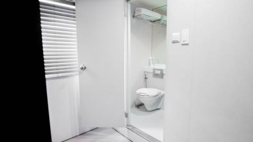 a white bathroom with a toilet and a shower at Green Sun Hotel in Manila