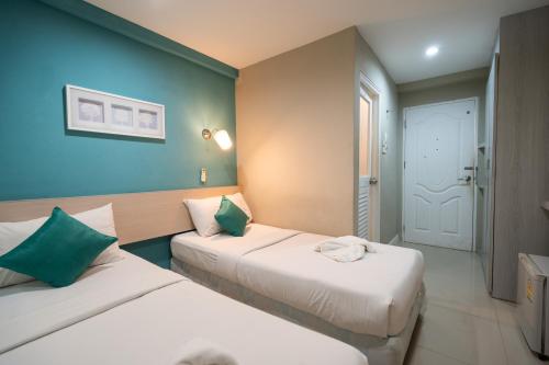 Duas camas num quarto com paredes azuis em V-Ocean Palace em Hat Yai