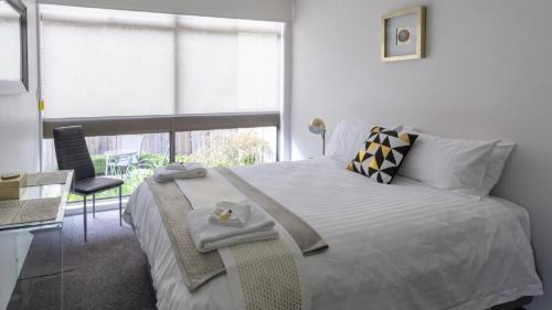 a bedroom with a bed with a table and a window at central park boutique apartment in Armidale