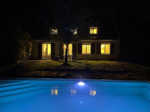 uma casa à noite com uma luz azul na frente em Jolie Villa avec piscine chauffée 8 par 4 m em Erdeven