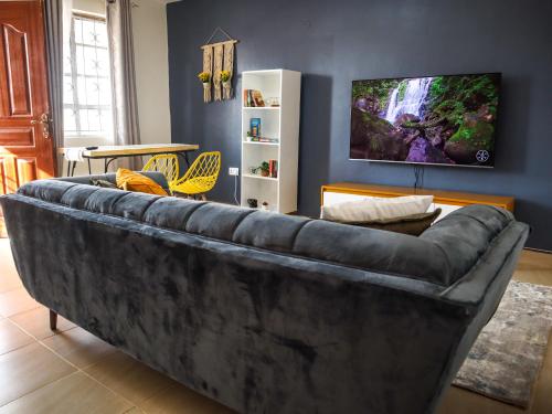 a large couch in a living room with a tv at Stunning 1-Bedroom Apartment in Madaraka Estate, Nairobi in Nairobi