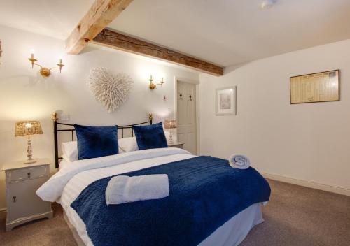 a bedroom with a large bed with blue pillows at Woodpecker Cottage in Pateley Bridge