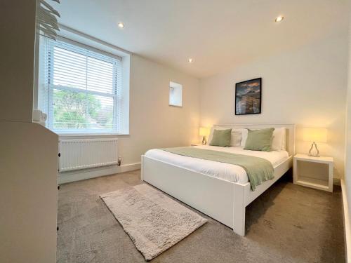 a bedroom with a large white bed and a window at Spacious Apartment~Parking~Close to Seafront in Penzance