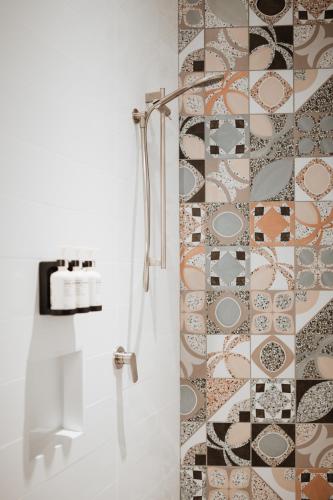 a bathroom with a shower with a tile wall at The Continental Hotel in Broome