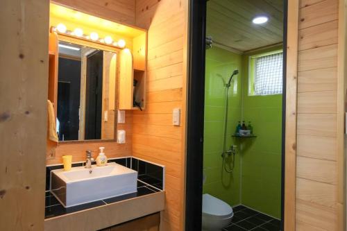 een badkamer met een wastafel, een toilet en een spiegel bij Taeheung Art Theater Pension in Seogwipo