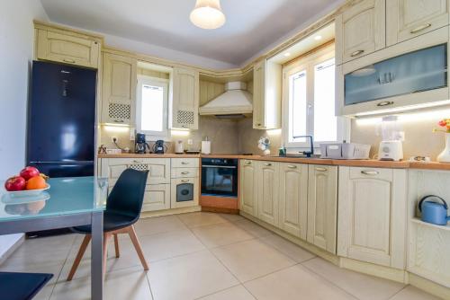 uma cozinha com armários brancos e uma mesa azul em Daphne's place em Vívlos