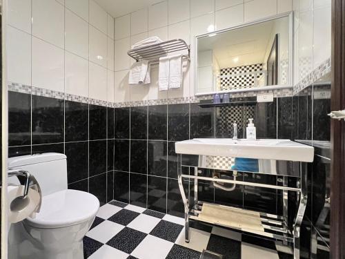 a black and white bathroom with a sink and a toilet at Kaishen Hotel in Taitung City