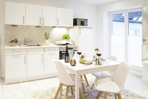 una cocina con armarios blancos y una mesa y sillas blancas. en Schwalbennest en Flensburg