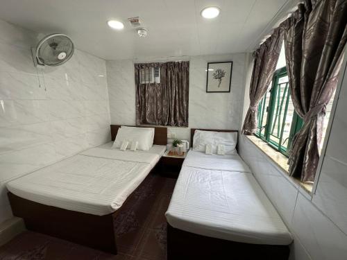 Mandarin Guest House في هونغ كونغ: سريرين في غرفة صغيرة بها نافذتين