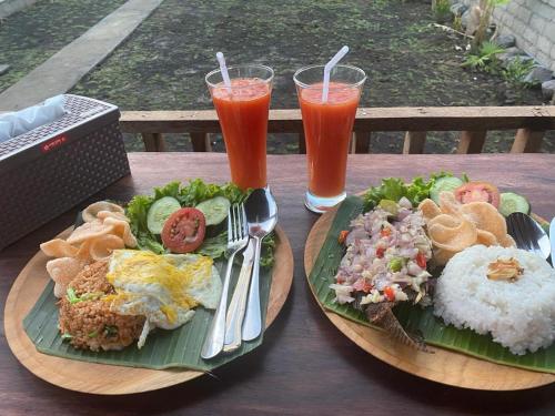 a table with two plates of food and two drinks at Pondok Bali Volcano in Kubupenlokan