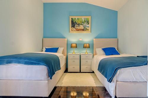 Duas camas num quarto com paredes azuis em Captains House em Fažana