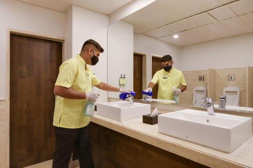 胡布利的住宿－Lemon Tree Hotel, Hubli，两个戴面罩的男人在浴室洗水槽