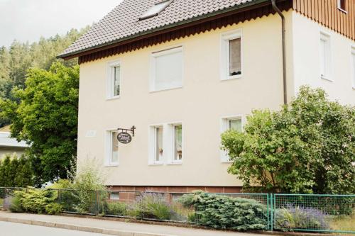 ein weißes Haus mit einem Zaun davor in der Unterkunft Liebevoll Gästewohnungen in Alpirsbach