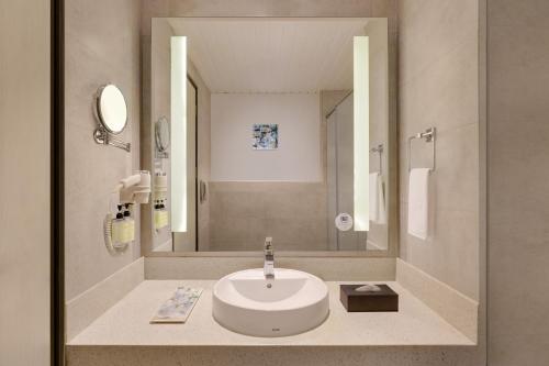 baño con lavabo y espejo grande en Lemon Tree Hotel, Hubli, en Hubli
