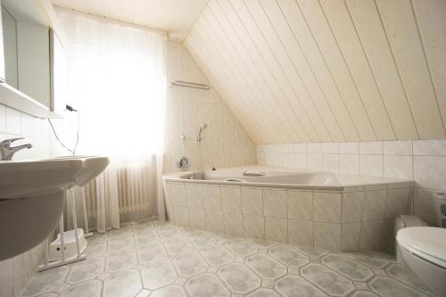 La salle de bains blanche est pourvue d'une baignoire et d'un lavabo. dans l'établissement Ferienhaus Blocksberg, à Braunlage