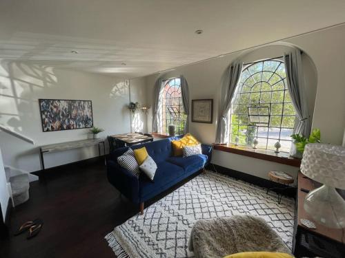 a living room with a blue couch and two windows at The Old Foundry Wallingford Apartment & Parking in Wallingford