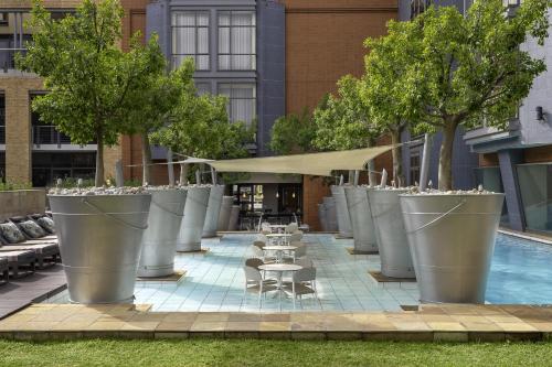 a row of large silver pots with tables and trees at African Pride Melrose Arch, Autograph Collection in Johannesburg