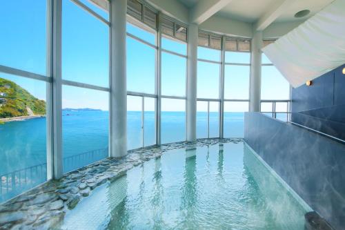 a swimming pool with a view of the ocean at Ooedo Onsen Monogatari Hotel Suiyotei in Atami