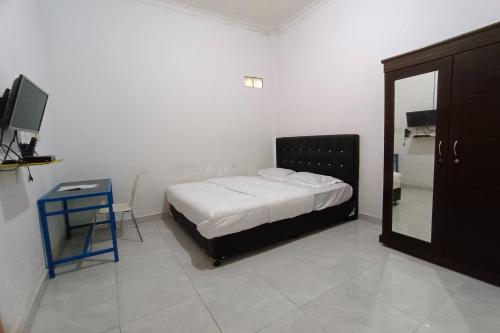 een slaapkamer met een bed, een tafel en een spiegel bij OYO 92833 Penginapan Syariah in Pekanbaru