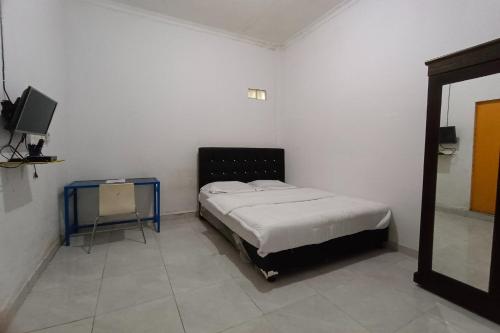 een slaapkamer met een bed en een tafel en een televisie bij OYO 92833 Penginapan Syariah in Pekanbaru