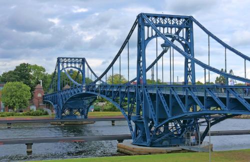 a blue bridge over a river next to the water at Sandkorn 1 in Wilhelmshaven
