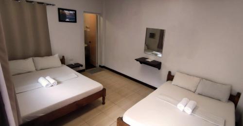 Cette chambre comprend 2 lits et une télévision. dans l'établissement Ginto Residence - City Center, à Coron