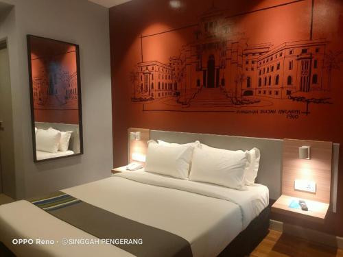 a bedroom with a bed with a painting on the wall at Singgah Pengerang Hotel in Pengerang