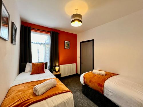 two beds in a room with orange walls at Oxford House - Tranquil Escape Hideaway in Cleethorpes