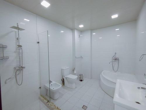 ein weißes Bad mit einer Dusche, einem WC und einem Waschbecken in der Unterkunft Izza Palace FAST WI-FI 120 MBPS in Taschkent