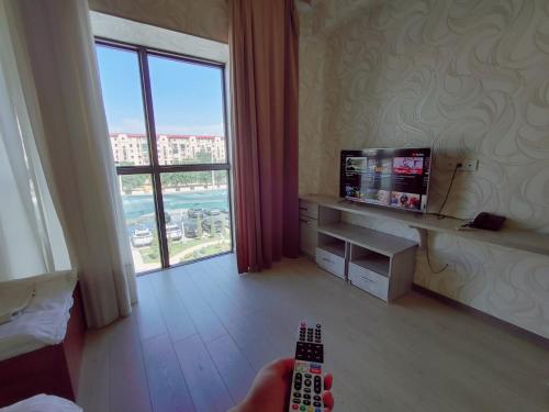 uma sala de estar com televisão e controlo remoto em IZZA PALACE Hotel em Tashkent