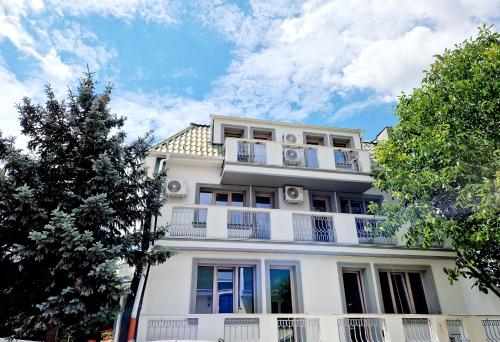 a white apartment building with balconies and trees at Atlantic Boutique in Târgu-Mureş