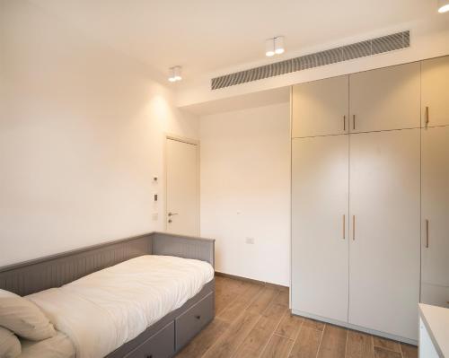 a bedroom with a bed and white cabinets at Hapalmah One, Jerusalem, Dira 4 in Jerusalem
