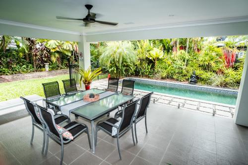 a dining room with a table and chairs and a pool at Chez Brolga in Port Douglas