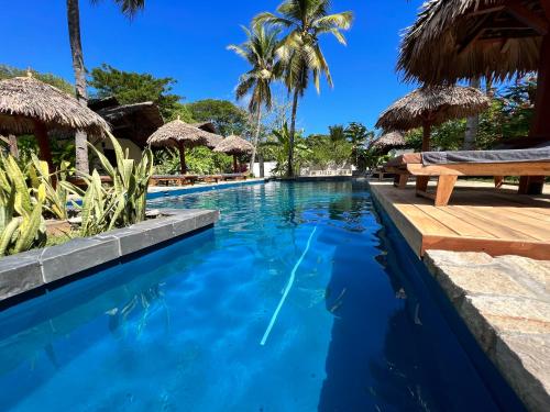 a swimming pool with benches and palm trees at NatShi Lodge in Ambaro