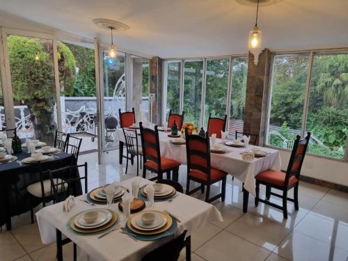 a dining room with tables and chairs and windows at Caribe Accommodation and Conferences in Pietermaritzburg