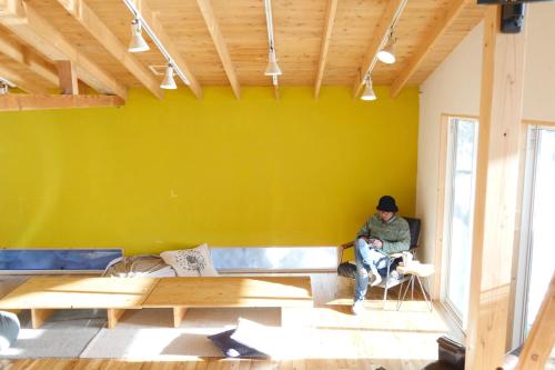 a man sitting in a chair in a room with a yellow wall at Lodge Free Run in Otari