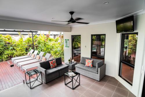 a living room with couches and a flat screen tv at Chez Brolga in Port Douglas