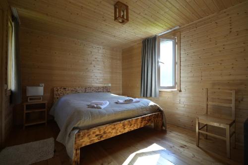 a bedroom with a bed in a wooden cabin at Cottages SHIKHRA - კოტეჯები შიხრა in Mazeri