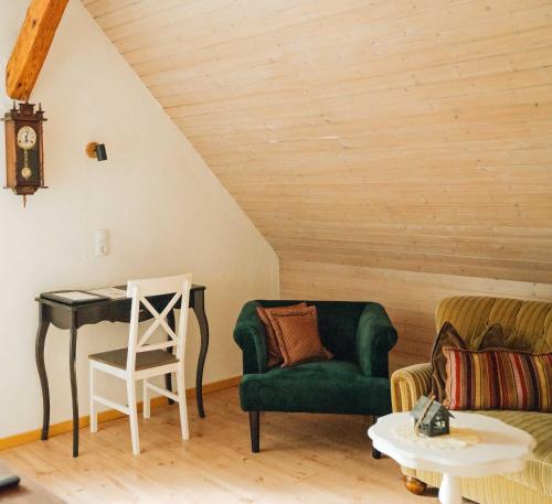 a living room with a green chair and a desk at Liebevoll Gästewohnungen in Alpirsbach
