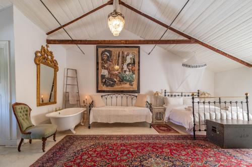 a bedroom with a tub and a bed and a chair at The Victorian of Church Street - Cape Dutch Quarters in Tulbagh
