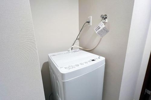 Una lavadora y secadora blancas en una esquina de un baño en Lafesta Higashikomagata, en Tokio