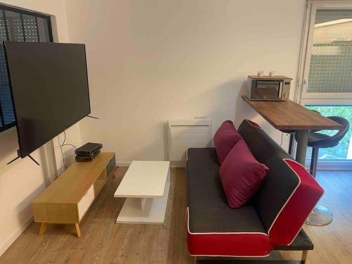 ein Wohnzimmer mit einem Sofa und einem Flachbild-TV in der Unterkunft Appart T2 bien équipé avec tram t1 et commodités à proximité 13 min du centre de Nantes in Saint-Herblain