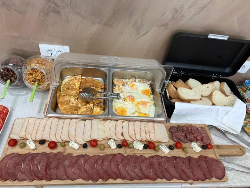 a table with sausage and eggs and other food at Apart-Hotel President in Ulcinj