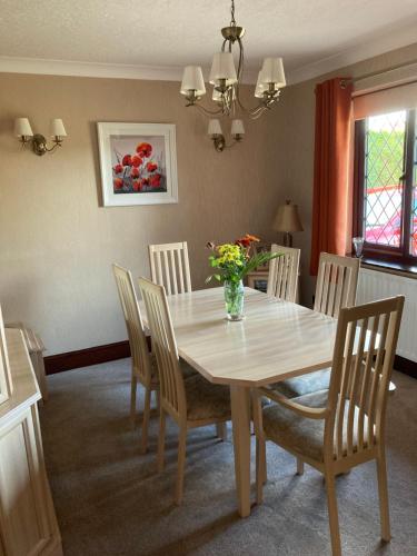 a dining room table with chairs and a vase of flowers on it at The Willows 