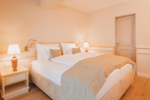 a bedroom with a large white bed and a night stand at MANNI das Hotel in Mayrhofen
