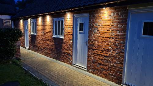 a brick house with a white door and lights at Kings Head in North Lopham